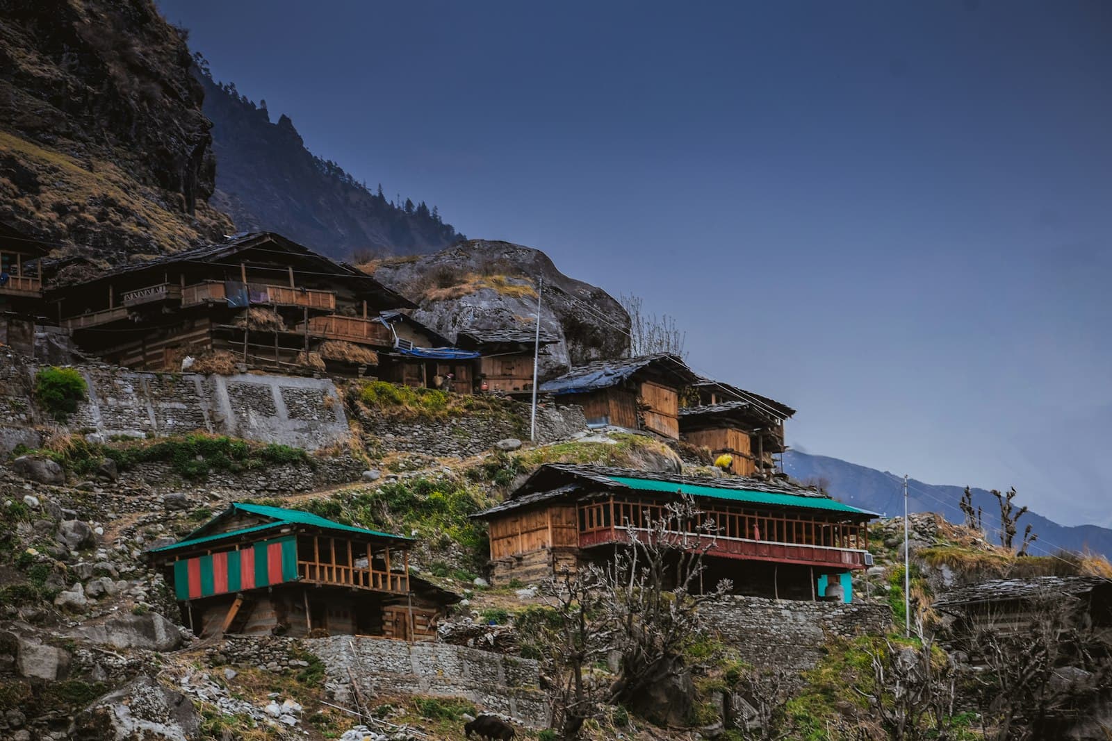 Traditional wooden houses with green roofs on a rocky Himalayan hillside