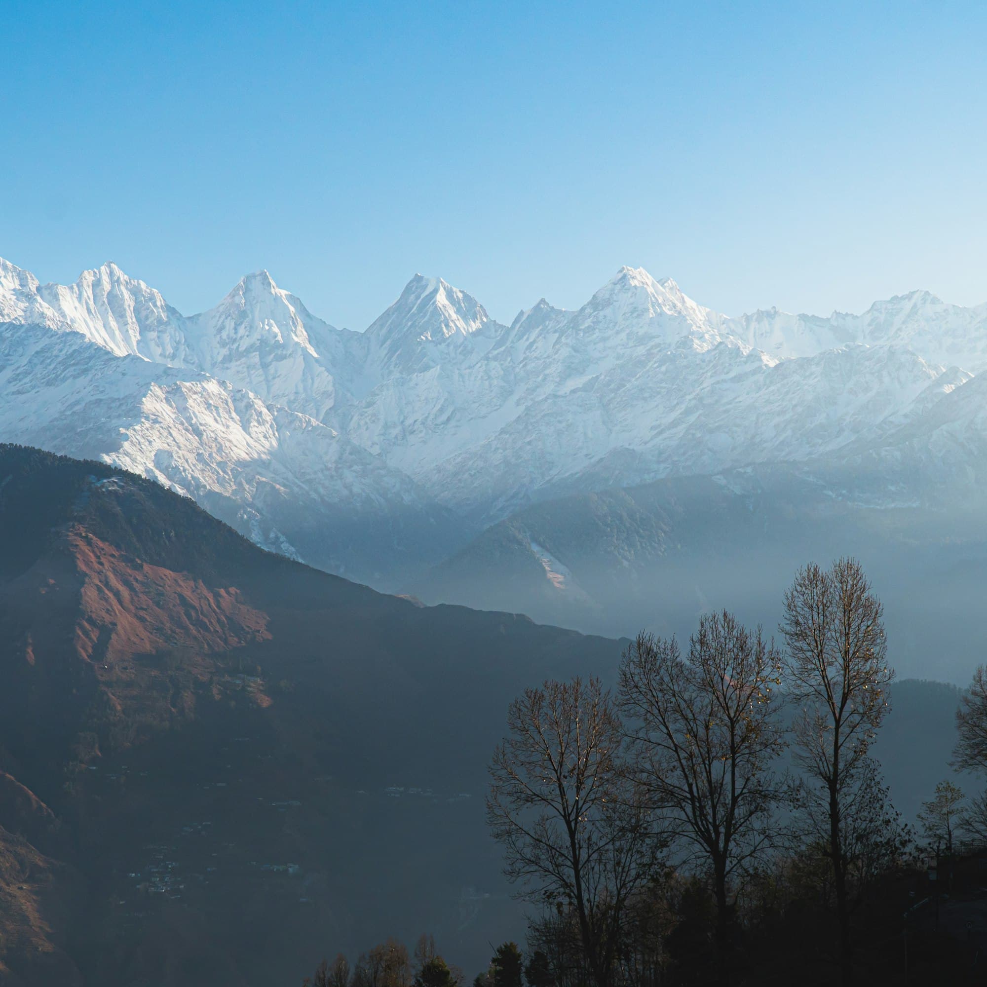 Snow-covered Himalayan peaks above forested ridges in Uttarakhand